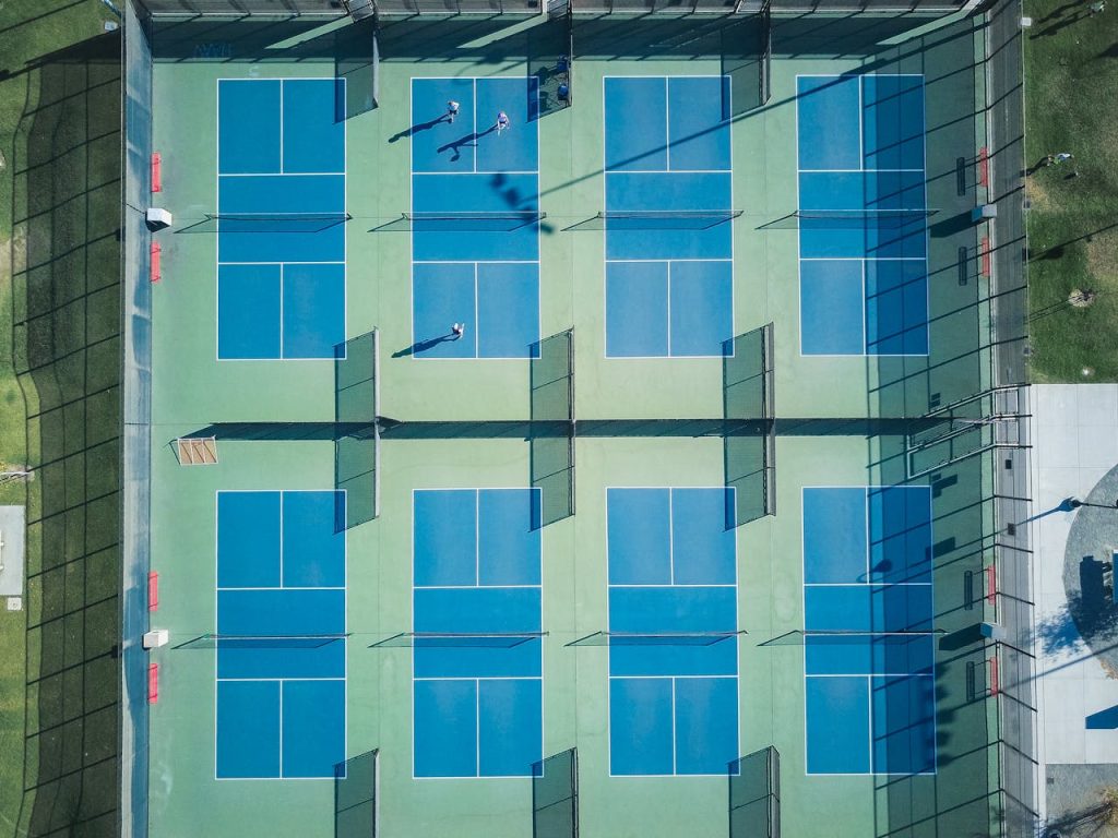 Drone shot of empty tennis courts with few players, top view perspective.